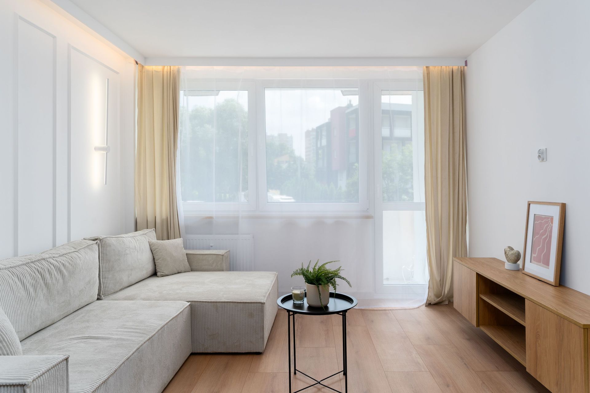 Bright minimalist living room in Kraków with modern decor, large windows, and natural light.